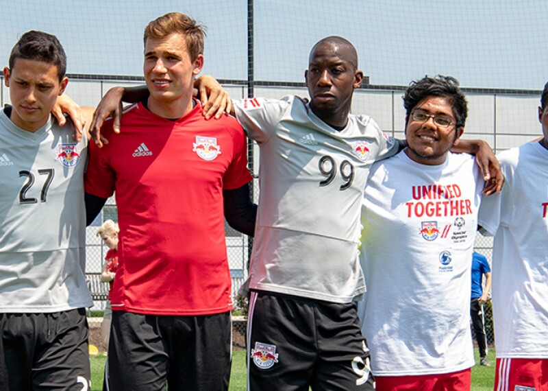 Group of footballers with their arms around one another's shoulders standing in a group. 