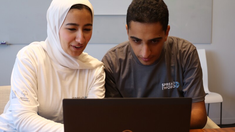 young man and mother figure are using a laptop. 