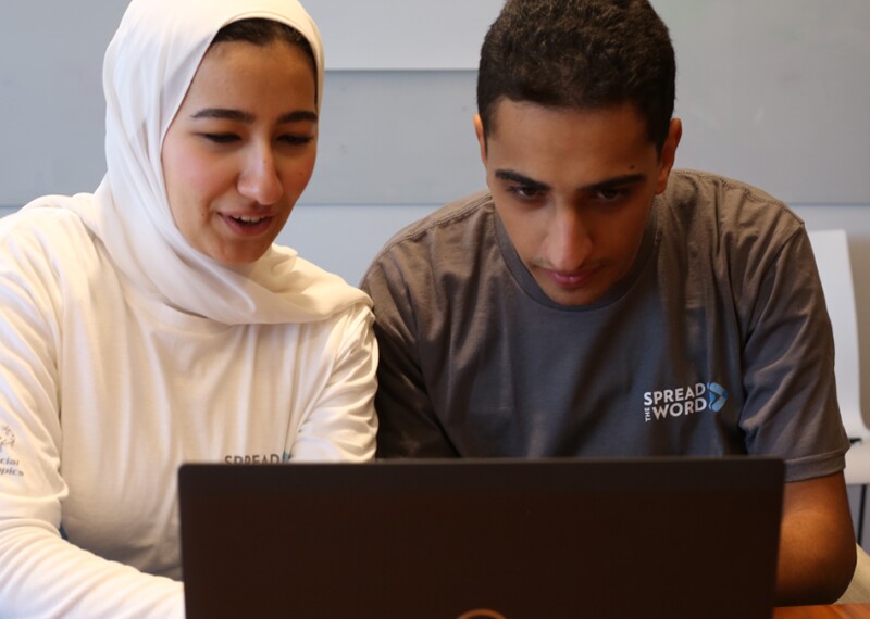 young man and mother figure are using a laptop. 