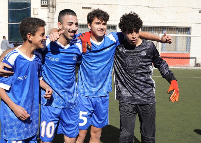 Four men with arms around each other’s shoulders in football gear