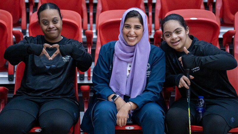 Three women side by side smiling and showing love. 