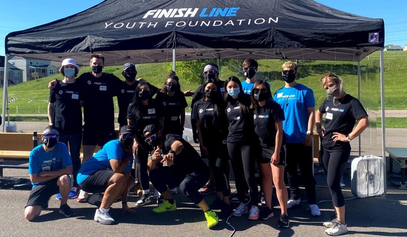 Group of people standing under a tent that reads: JD Finish Line