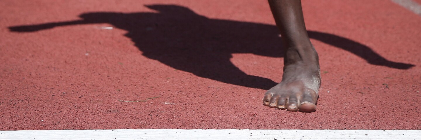 Person running, foot is about to cross a white line on the track. 