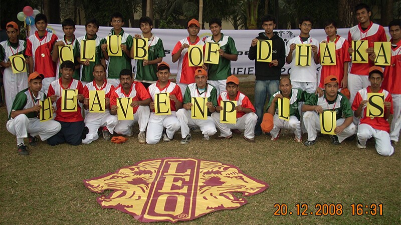 Two rows of people the back row standing and the front row crouching hold up individual up letters that spell out "O Club of Dhaka Heaven Plus"