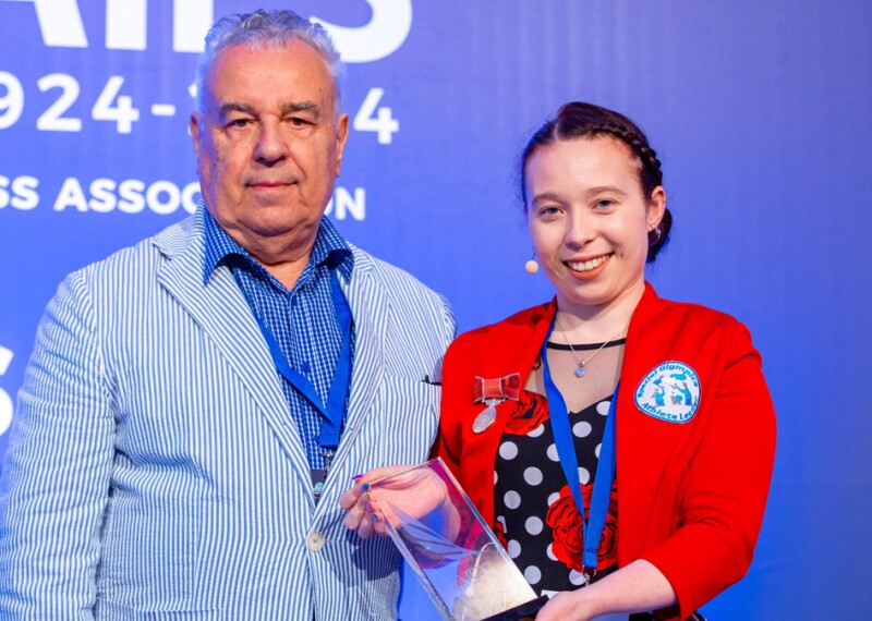 Woman holding an award and standing next to a man.