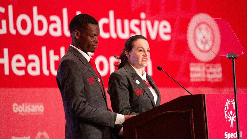 One man and one woman standing at podium speaking into microphone.