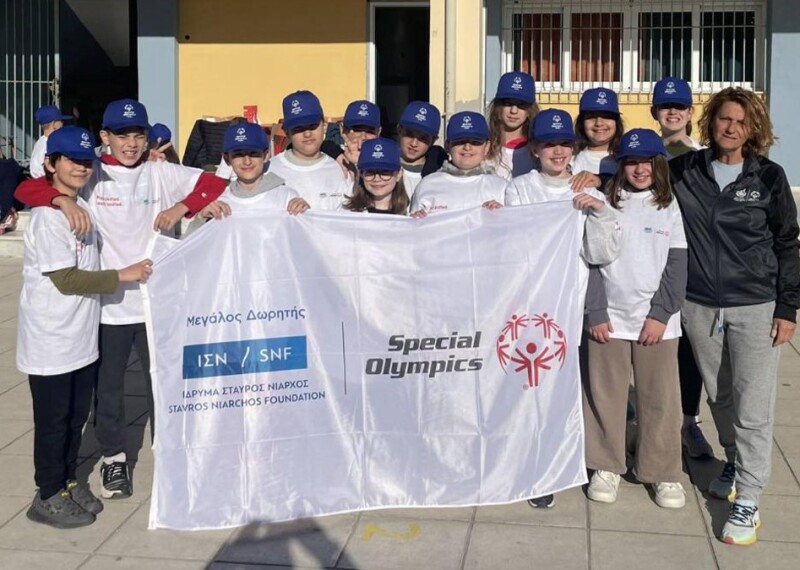 Teacher students showing their support for Special Olympics and holding a Special Olympics branded flag. 