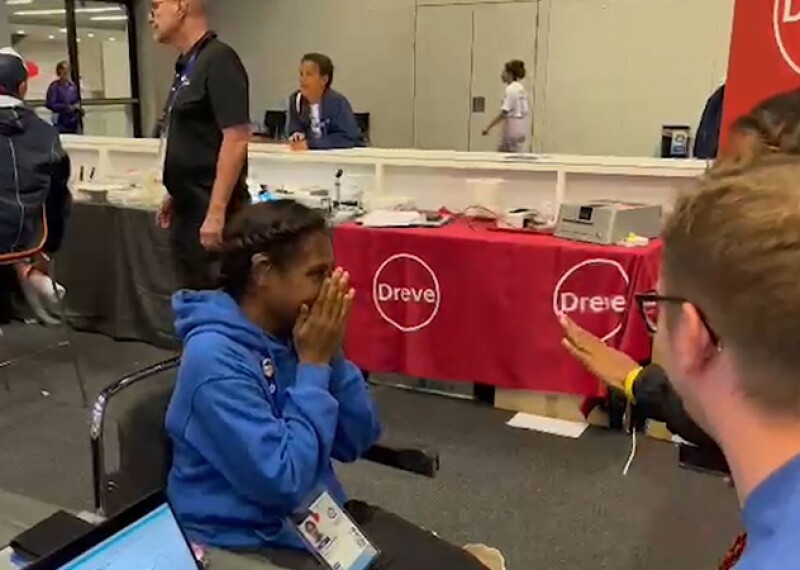 Young woman covering her mouth and nose in emotion; it's the first time she is able to hear. 