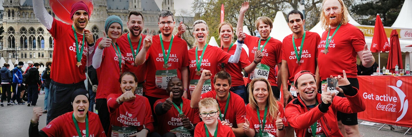 A group of people in red Special Olympics shirts standing together in two rows for a group photo. 