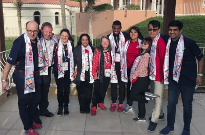 10  young adults standing outside with their arms around one another smiling. 