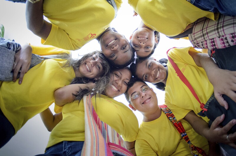 A ground of athletes standing in a circle looking down and smiling. 