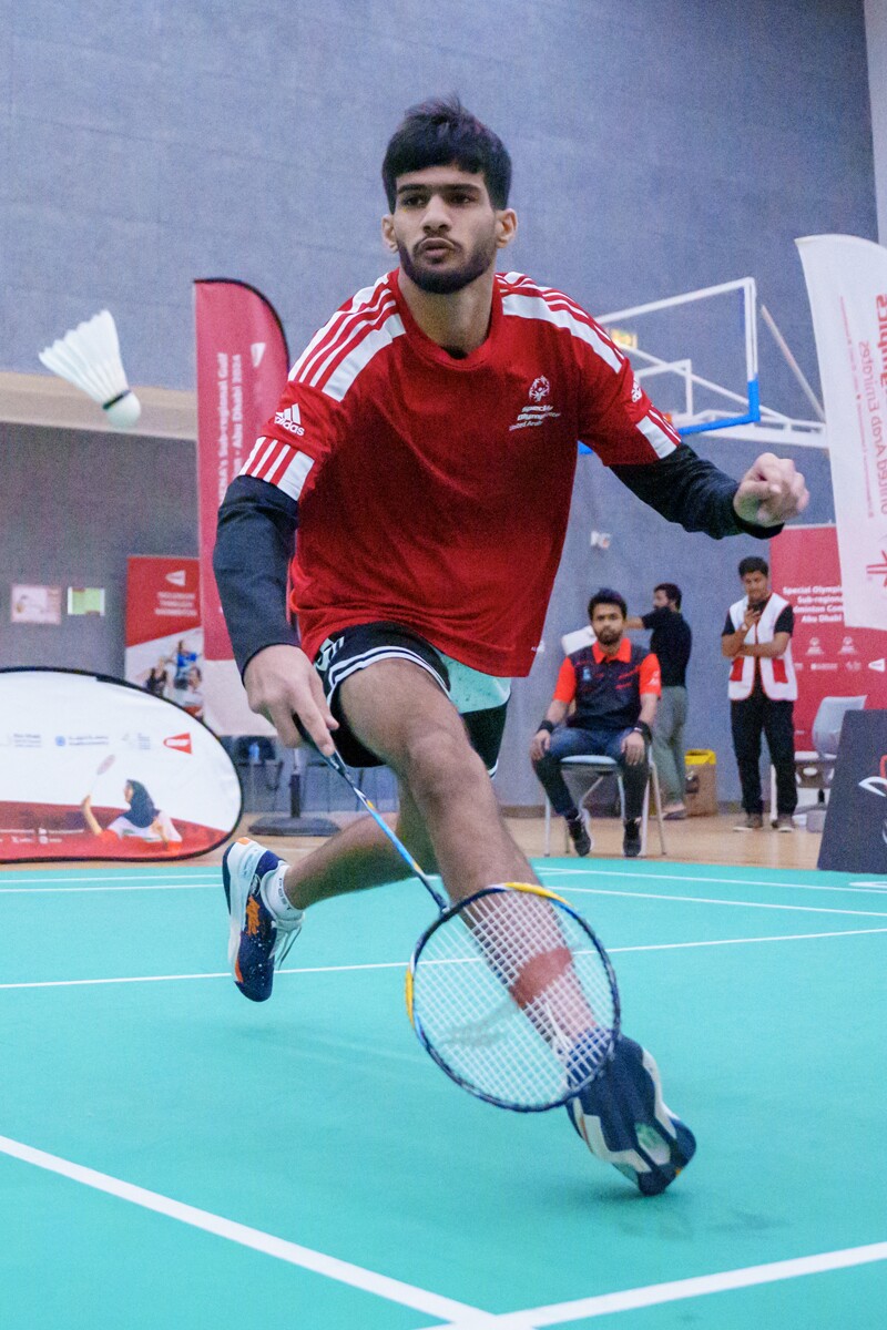 Man playing badminton and running for the birdie. 