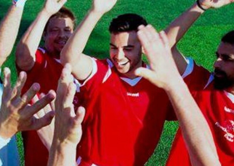 Players on a field celebrating and giving one another high-5s. 