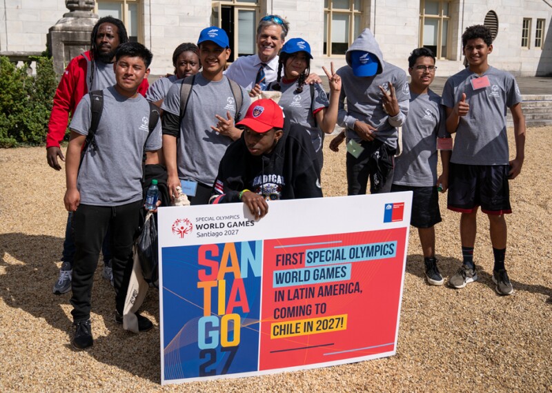 A small group of athletes and Tim Shriver holding up a Chile 2027 poster. 