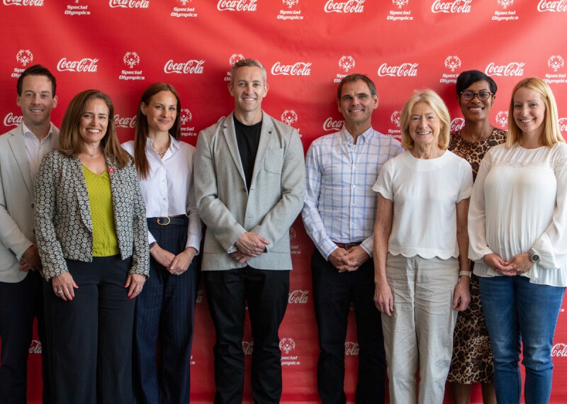 8 male and female Special Olympics and Coke-Cola representatives standing side by side. 