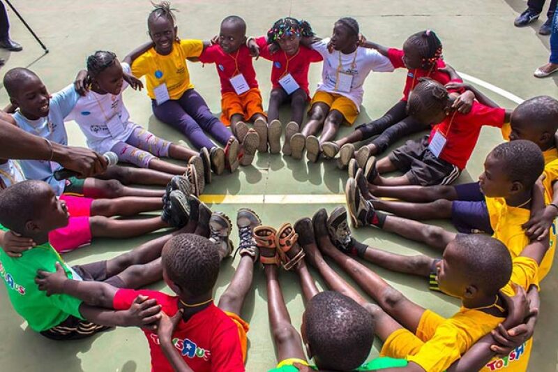 young athletes sitting in a circle with their feet together forming another circle. 