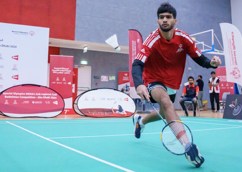 Man playing badminton and running for the birdie. 