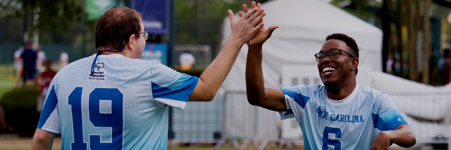 Two athletes giving one another a high 5.