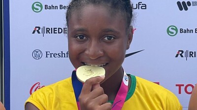 Young woman biting her gold medal. 