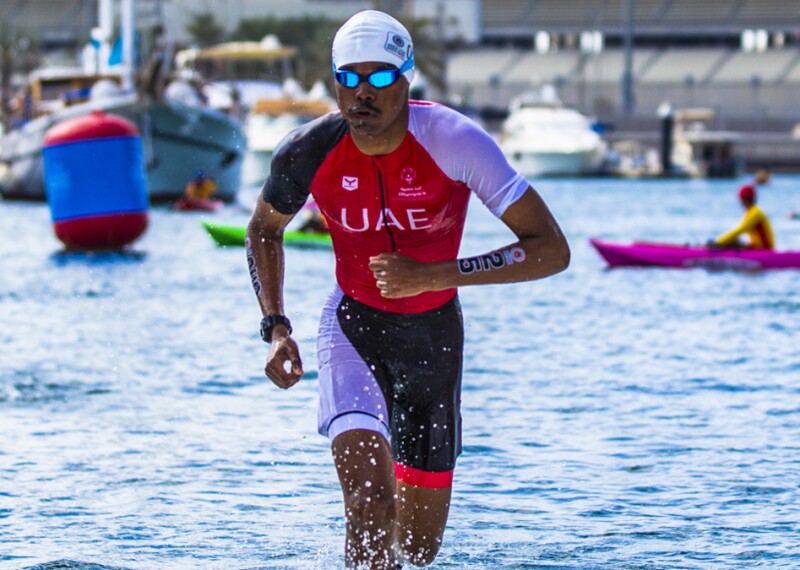 Triathlete man running out of the water. 