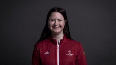 Woman wearing Special Olympics red jacket smiles at the camera