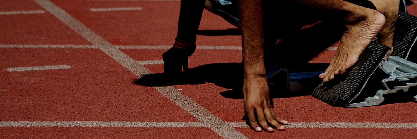 A runner taking their mark on a race track. 