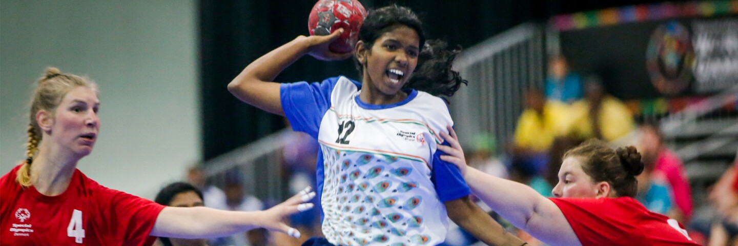 Three young women playing a game of handball. 