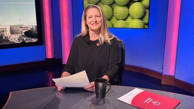 Kim Widdess sitting at a news desk at Comcast. 