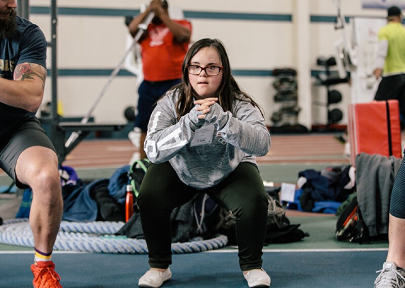 Athletes performing squats in a gym. 