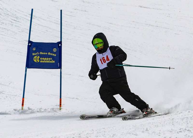 A Special Olympics athlete races down a snowy mountain on skis. 