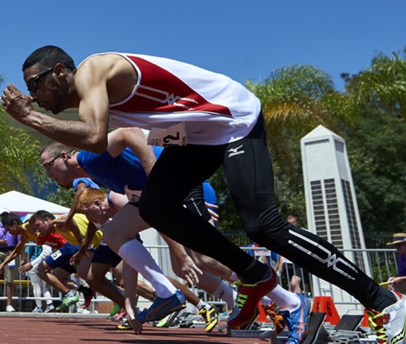 Male athletes taking their mark and start off running on the track. 